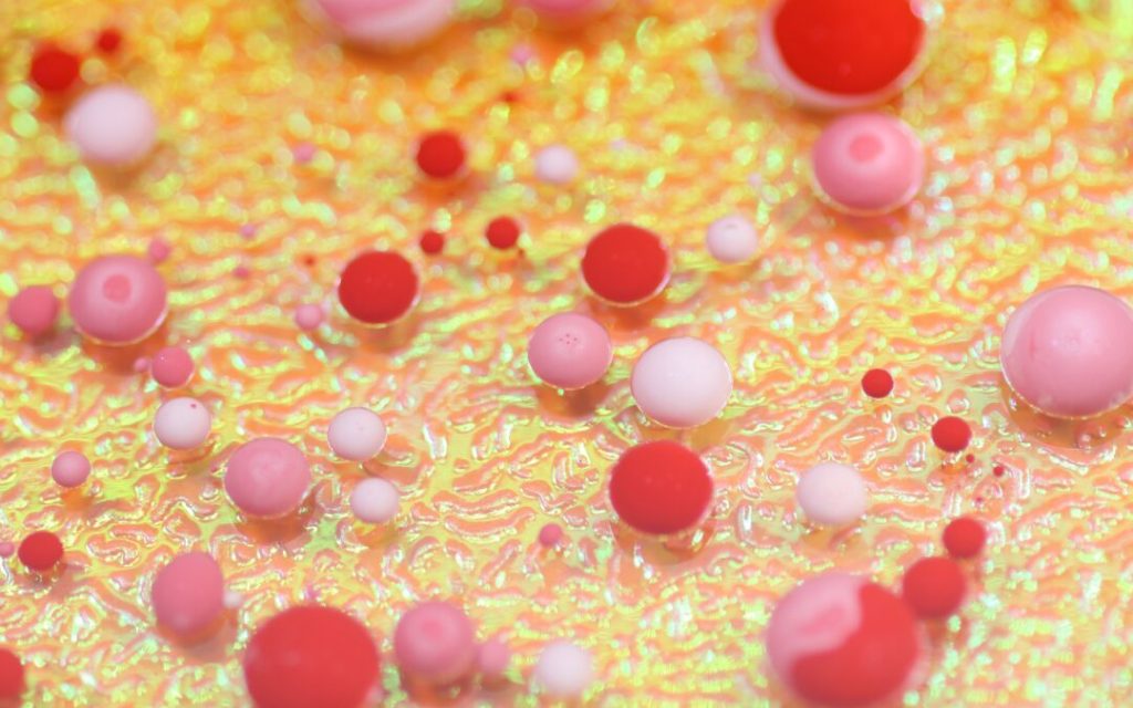 Pink red and white spheres of different shapes against an irradiated material.