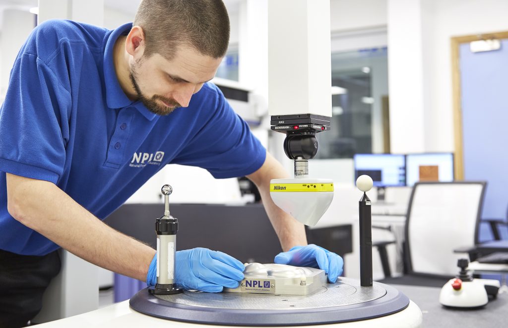 A man positioning a metal part on a CMM.